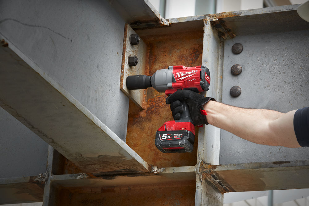 Strângere a unor șuruburi pe o structură metalică cu ajutorul unei chei cu impact Milwaukee M18 FUEL, ideală pentru aplicații grele în construcții și șantier.